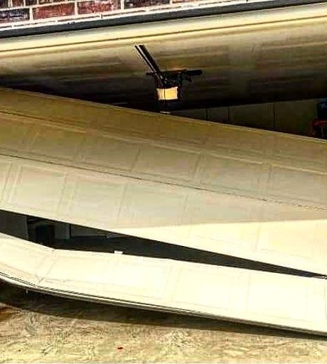 Garage door panels bent and pushed off track inside a garage