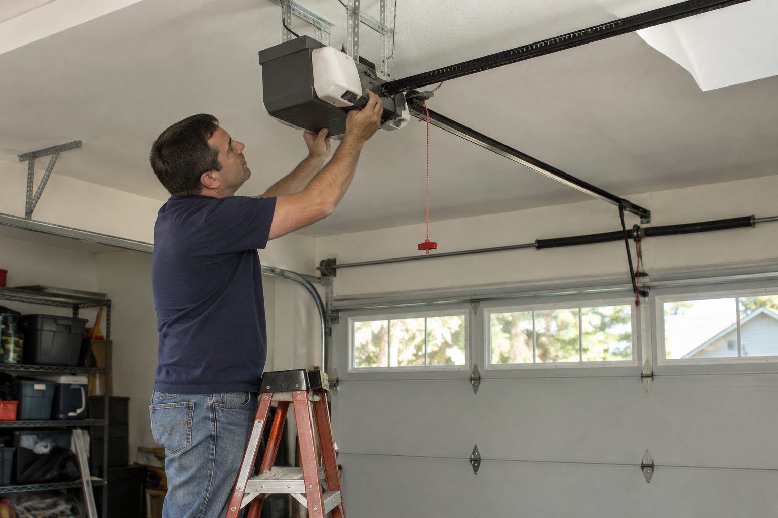 Technician adjusting a garage door opener motor on a garage ceiling